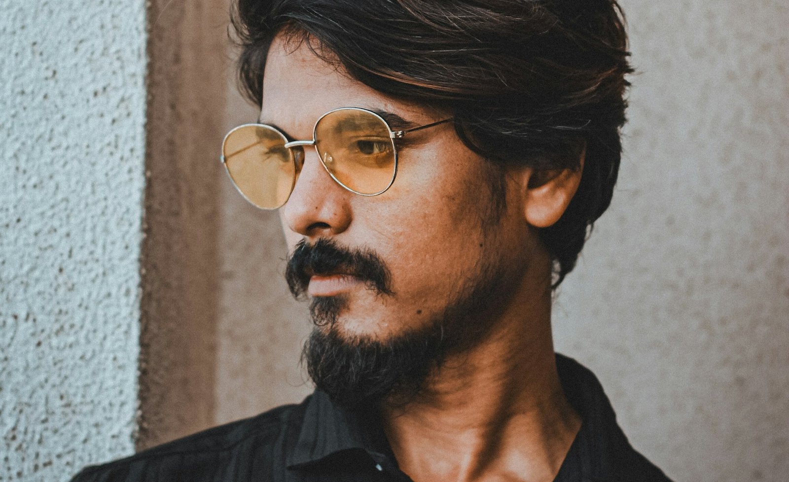 Bearded Indian model in a black shirt with round glasses